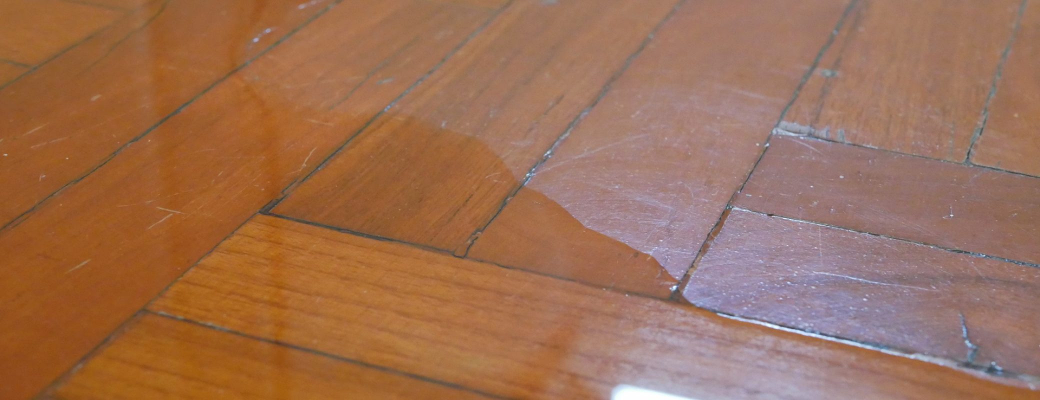 Close up of water spreading / flooding on the parquet floor of a house - damage caused by water leakage